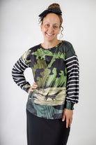 Model wearing the Nuggles® Jaxon Bryauna Top, a long-sleeve modest shirt with dinosaur and stripe print, styled for everyday wear and created as part of a fundraiser in honor of Jaxon.