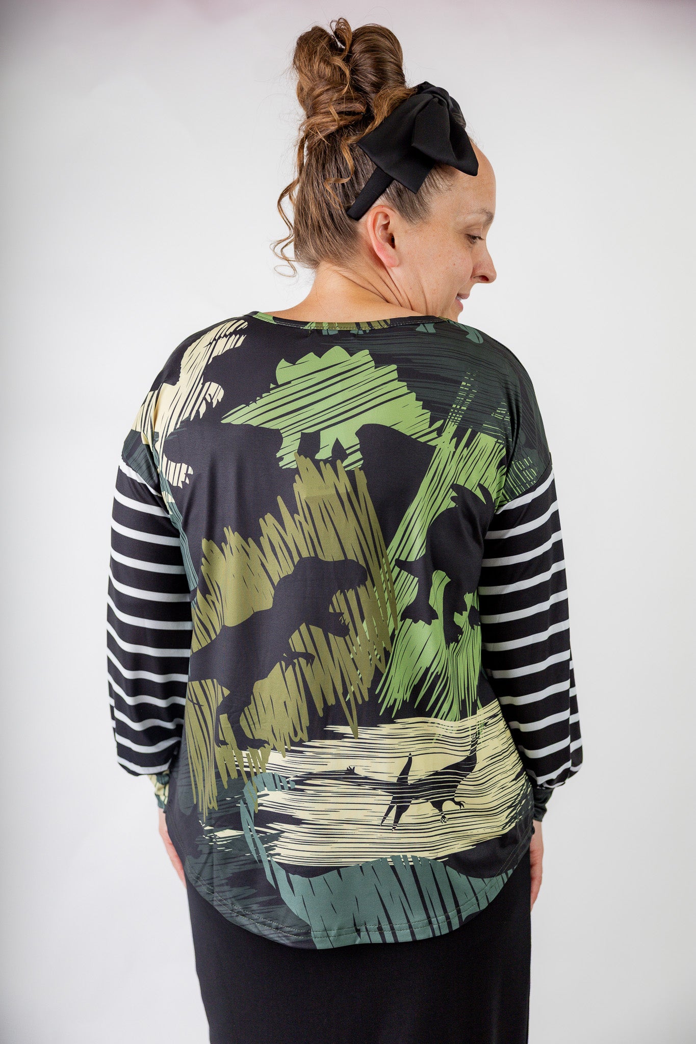 Model wearing the Nuggles® Jaxon Bryauna Top, a long-sleeve modest shirt with dinosaur and stripe print, styled for everyday wear and created as part of a fundraiser in honor of Jaxon.