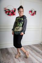 Model wearing the Nuggles® Jaxon Bryauna Top, a long-sleeve modest shirt with dinosaur and stripe print, styled for everyday wear and created as part of a fundraiser in honor of Jaxon.