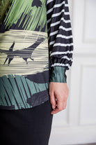 Model wearing the Nuggles® Jaxon Bryauna Top, a long-sleeve modest shirt with dinosaur and stripe print, styled for everyday wear and created as part of a fundraiser in honor of Jaxon.