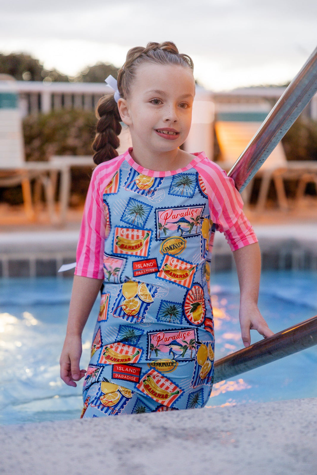 Model wearing Nuggles® Girls' Sport Swim Dress in Vacation Postcards