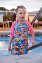 Model wearing Nuggles® Girls' Sport Swim Dress in Vacation Postcards