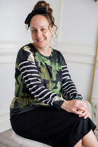 Model wearing the Nuggles® Jaxon Bryauna Top, a long-sleeve modest shirt with dinosaur and stripe print, styled for everyday wear and created as part of a fundraiser in honor of Jaxon.