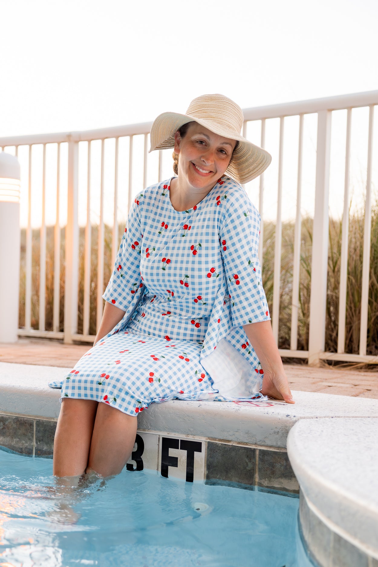 Model wearing Nuggles® Carlie Swim Dress in Sweet Cherry Check