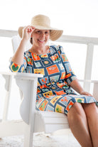 Model wearing Nuggles® Nola Sport Swim Dress in Retro Postcards