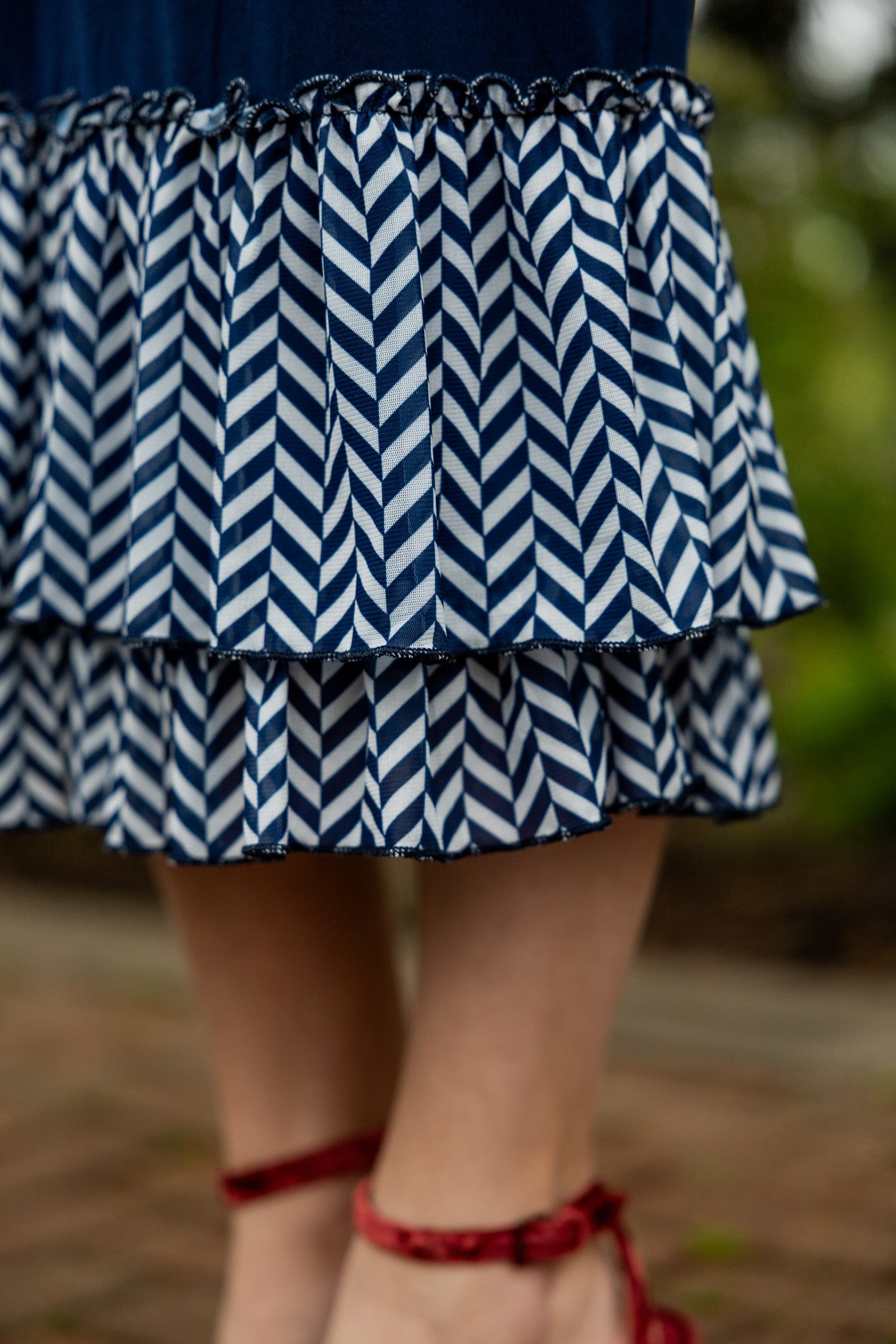 Navy 27" slip skirt with double ruffle hem in white and navy chevron pattern, styled with a beige top.