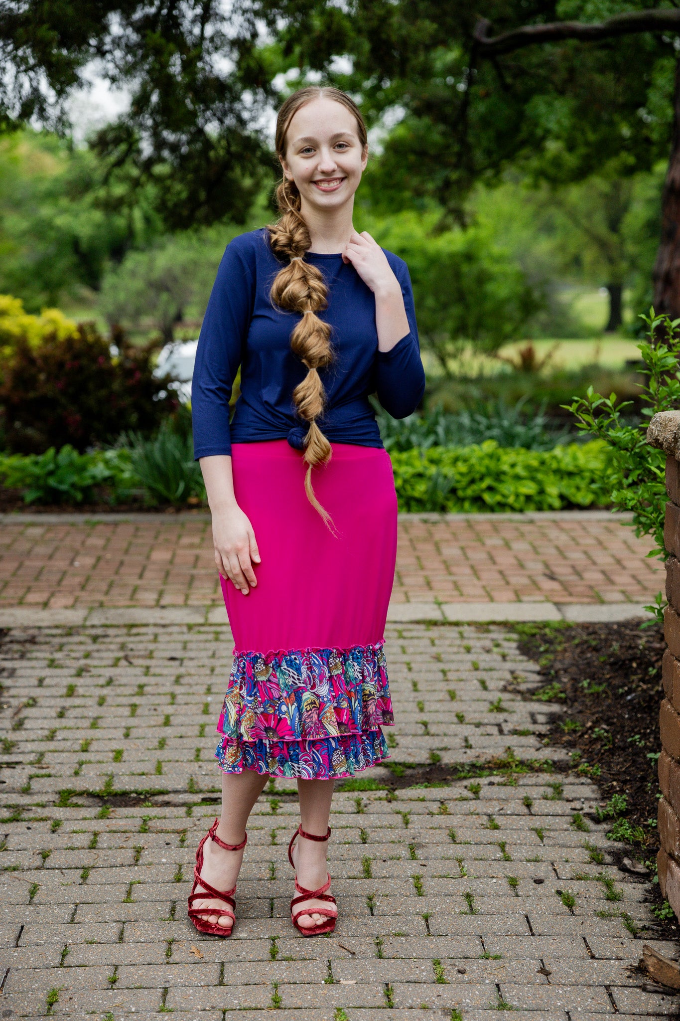 Model wearing a bright magenta 27" slip skirt with a colorful tropical floral ruffle design.