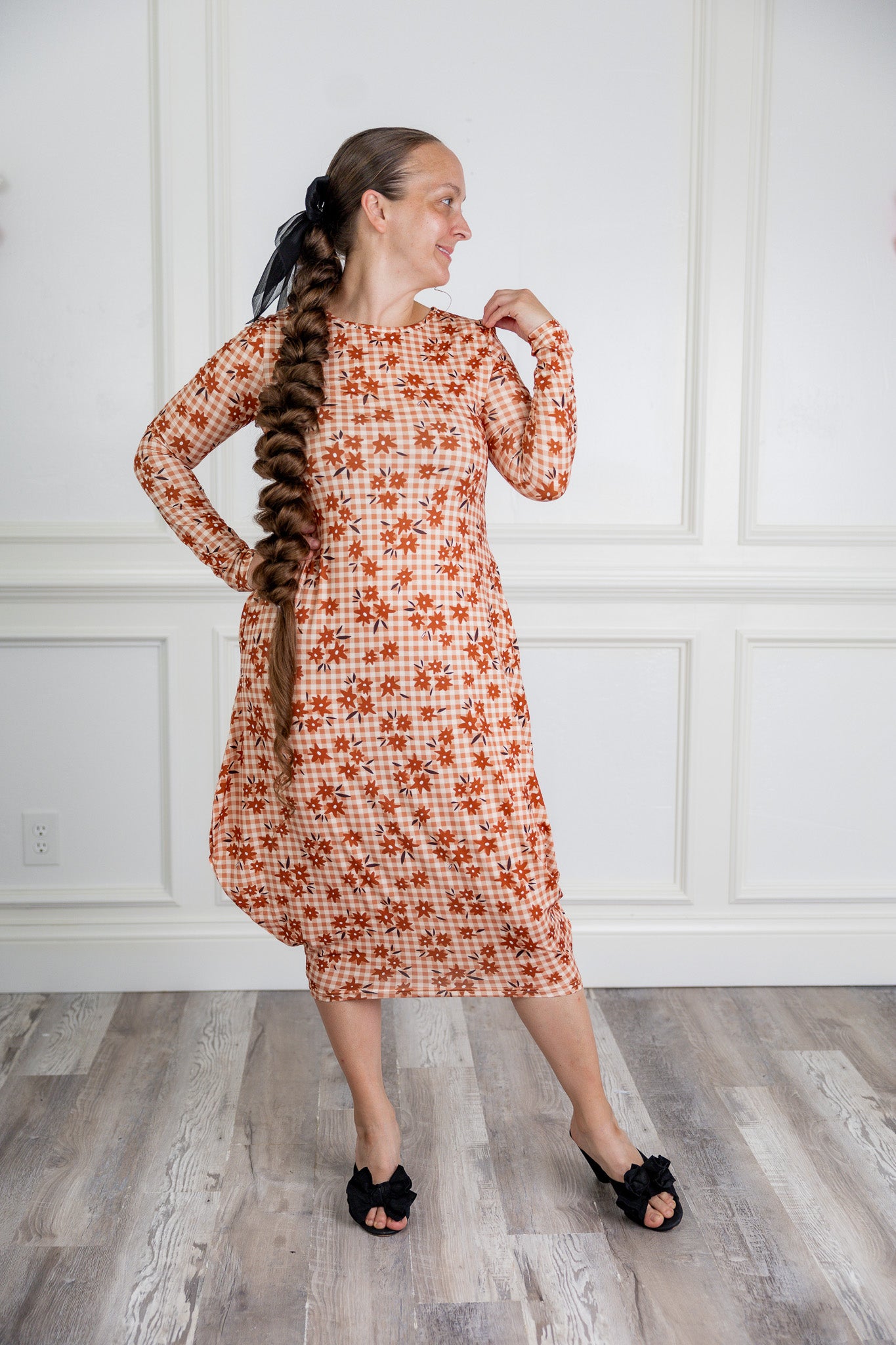 Woman modeling a Nuggles pattern midi dress made from soft, stretchy knit fabric, featuring long sleeves and side pockets.