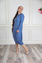 Woman modeling a Nuggles blue pattern midi dress made from soft, stretchy knit fabric, featuring long sleeves and side pockets.