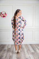 Woman modeling a Nuggles floral print midi dress made from soft, stretchy knit fabric, featuring long sleeves and side pockets.