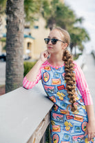 Model wearing Nuggles® Sport Swim Dress in Vacation Postcards