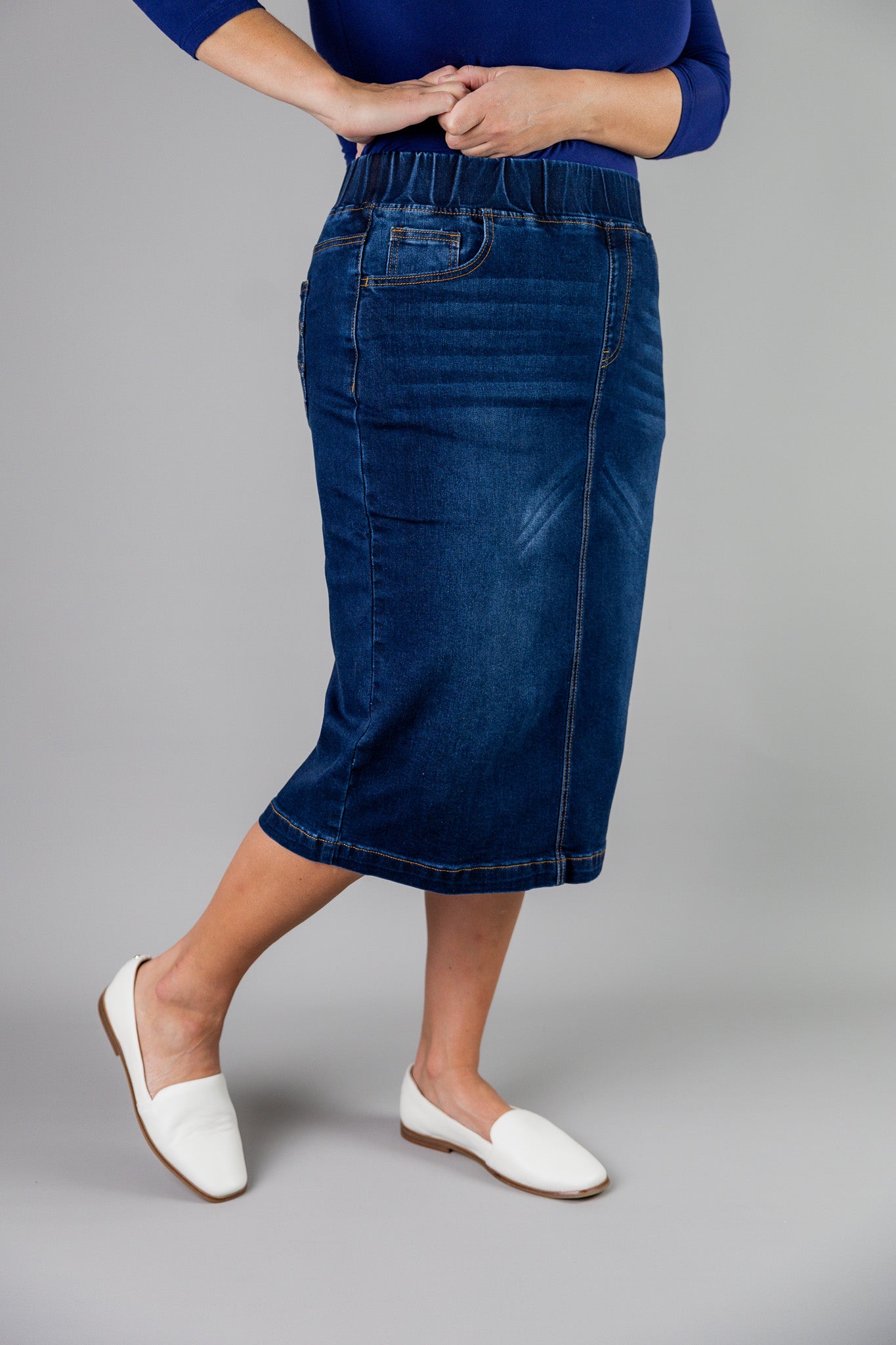 Nuggles® denim midi skirt with soft stretch fabric, wide elastic waistband, modest length, and functional pockets. Available in 27", 31", and 34" lengths.