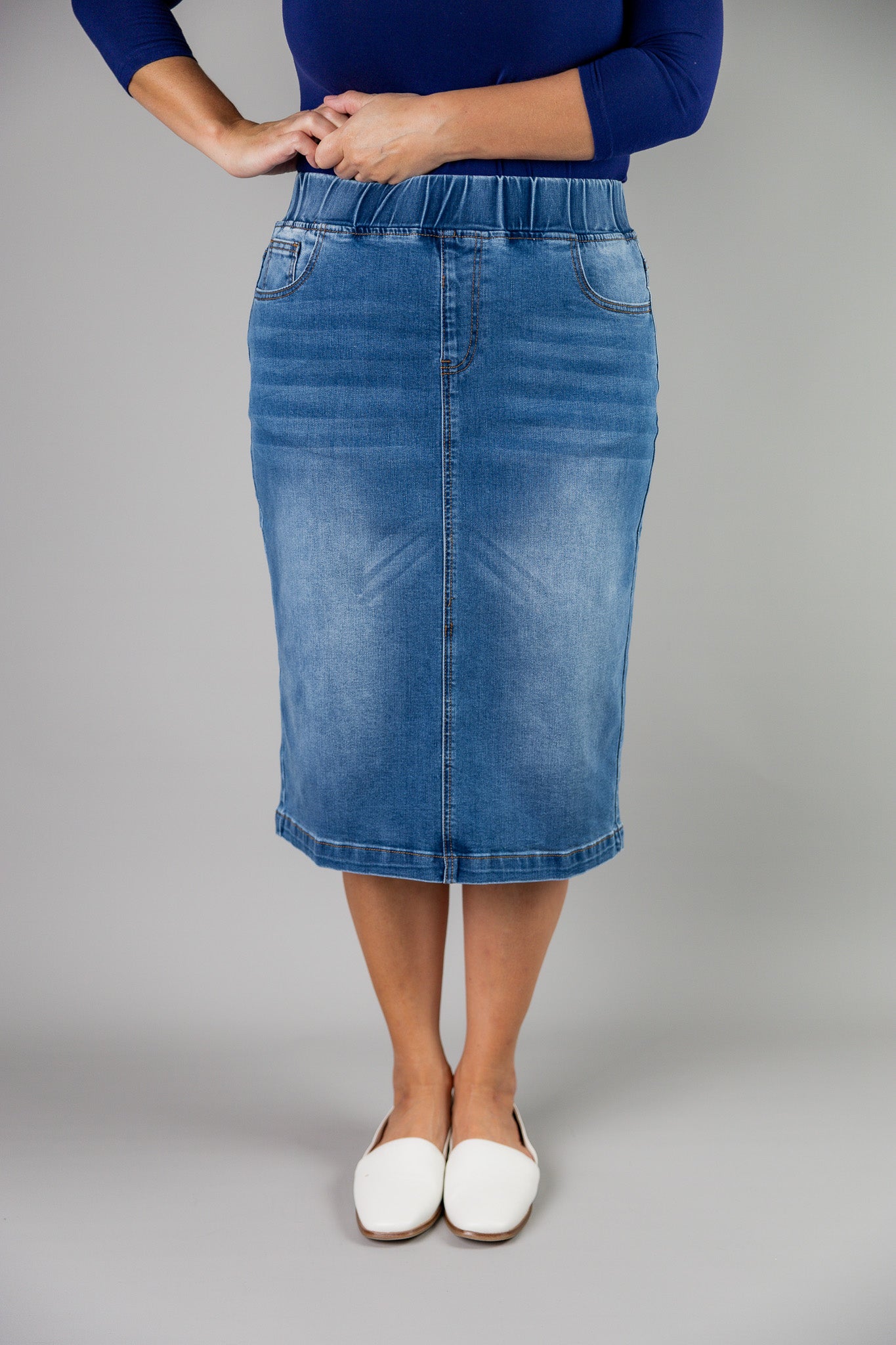 Nuggles® denim midi skirt with soft stretch fabric, wide elastic waistband, modest length, and functional pockets. Available in 27", 31", and 34" lengths.