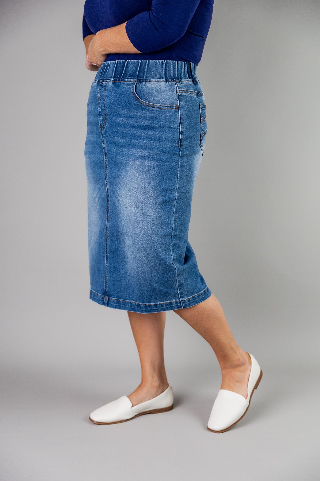 Nuggles® denim midi skirt with soft stretch fabric, wide elastic waistband, modest length, and functional pockets. Available in 27", 31", and 34" lengths.