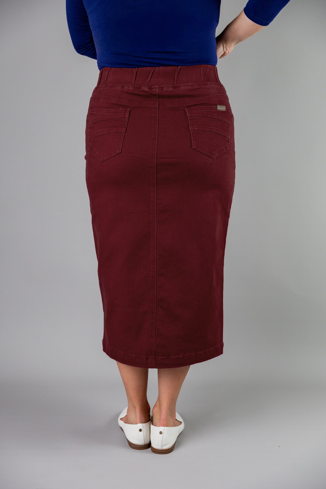 Nuggles® denim midi skirt with soft stretch fabric, wide elastic waistband, modest length, and functional pockets. Available in 27", 31", and 34" lengths.