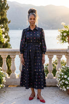 A picture of an older women wearing a blue button down dress. 