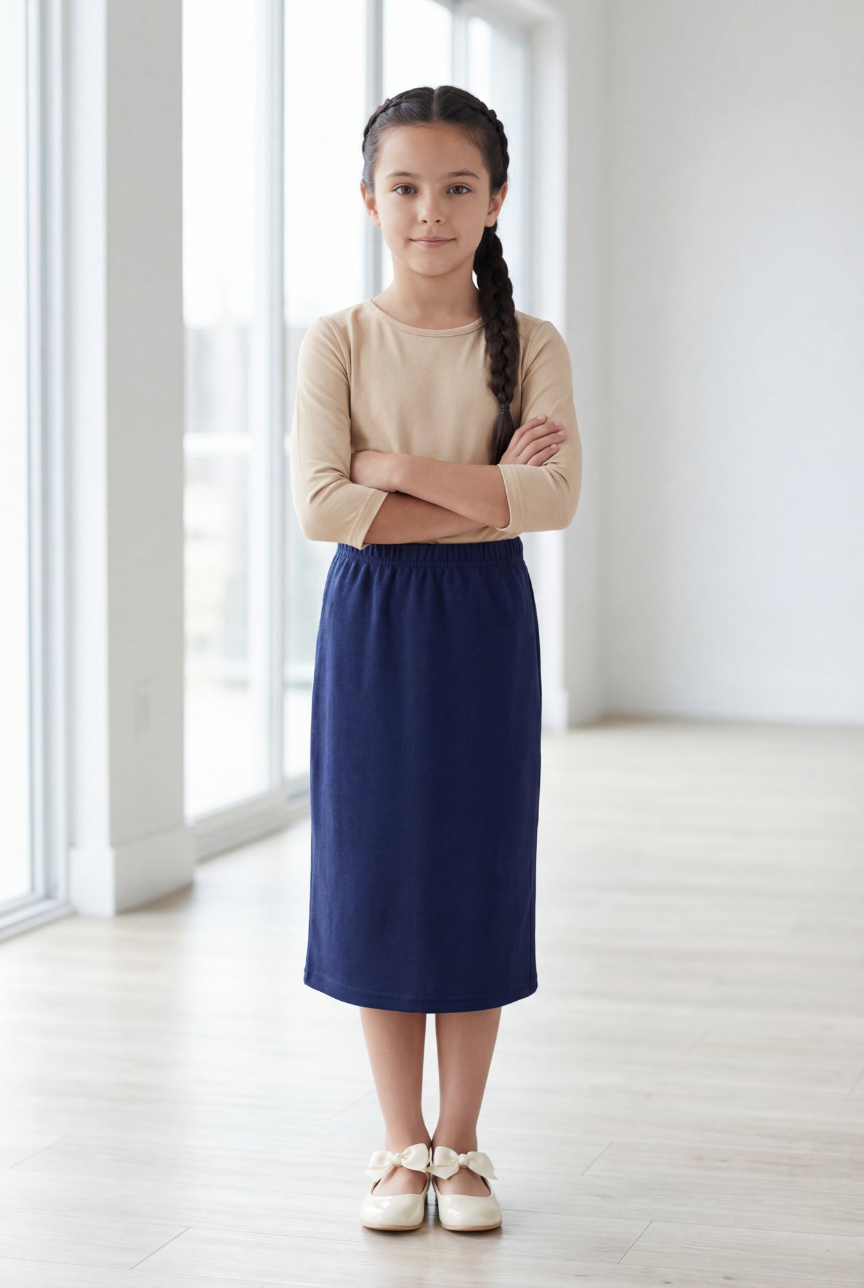 Young girl wearing a modest midi length skirt in navy with a beige colored 3/4 length sleeve shirt. 