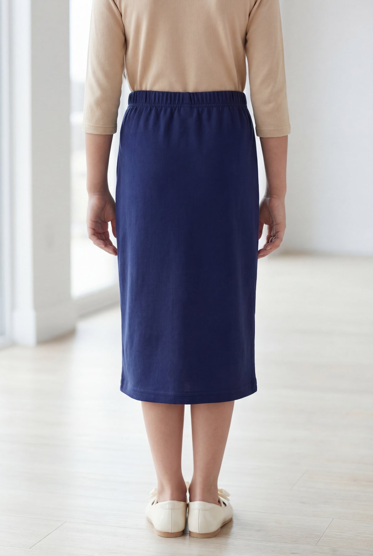 Young girl wearing a modest midi length skirt in navy with a beige colored 3/4 length sleeve shirt. 