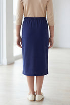 Young girl wearing a modest midi length skirt in navy with a beige colored 3/4 length sleeve shirt. 