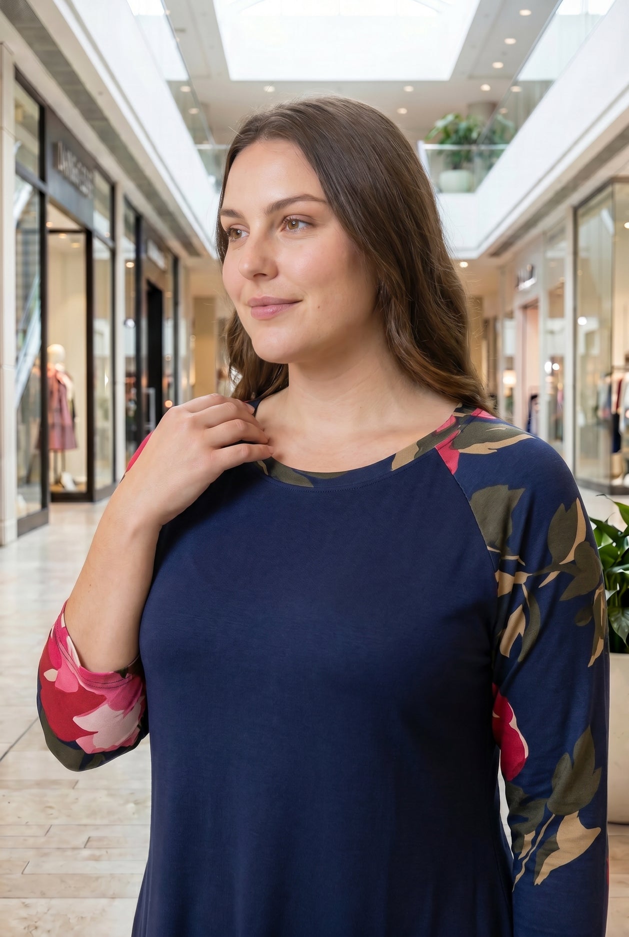 Woman modeling a navy floral-sleeve top in a mall.