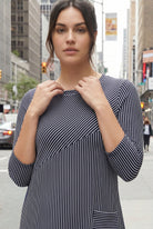 Woman wearing a black and white striped dress on a city street.
