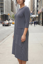 Woman wearing a blue and white striped dress on a city street.
