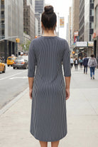 Woman in a striped dress standing on a city street