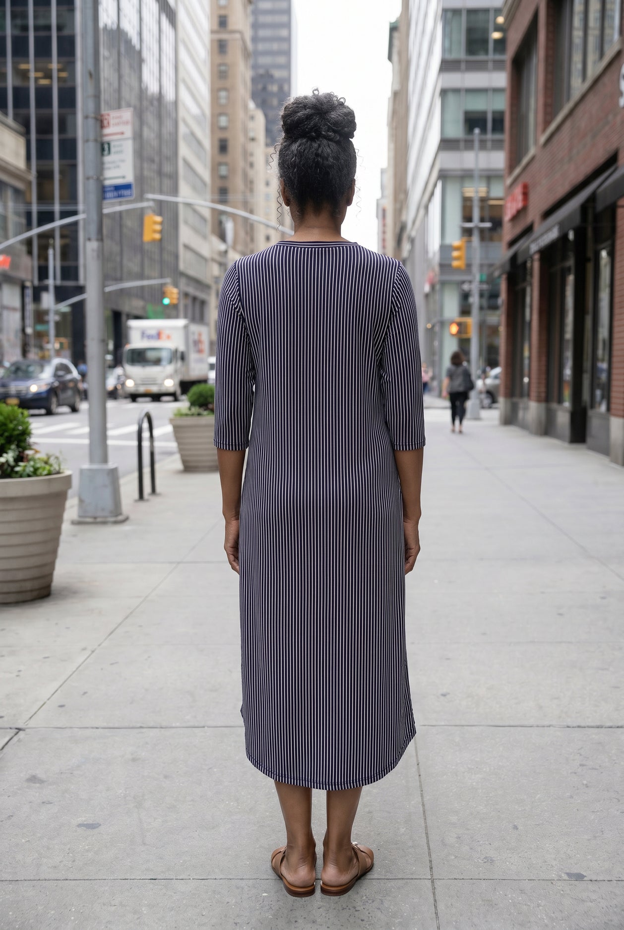 Women standing in a navy and pink stripe dress on a busy city street. 