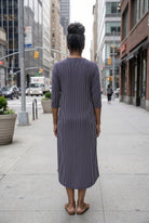 Women standing in a navy and pink stripe dress on a busy city street. 