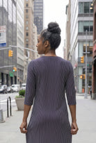 Women standing in a navy and pink stripe dress on a busy city street. 