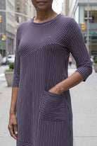Women standing in a navy and pink stripe dress on a busy city street. 