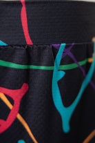 Close-up of black leggings with colorful abstract designs on a plain background