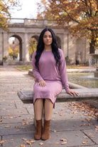 Nuggles® Oakley Hoodie Dress in Pale Purple, seated facing forward on a stone bench in a fall park