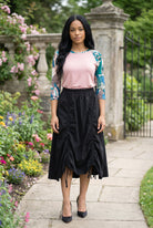 Woman in a garden wearing a floral top and black skirt