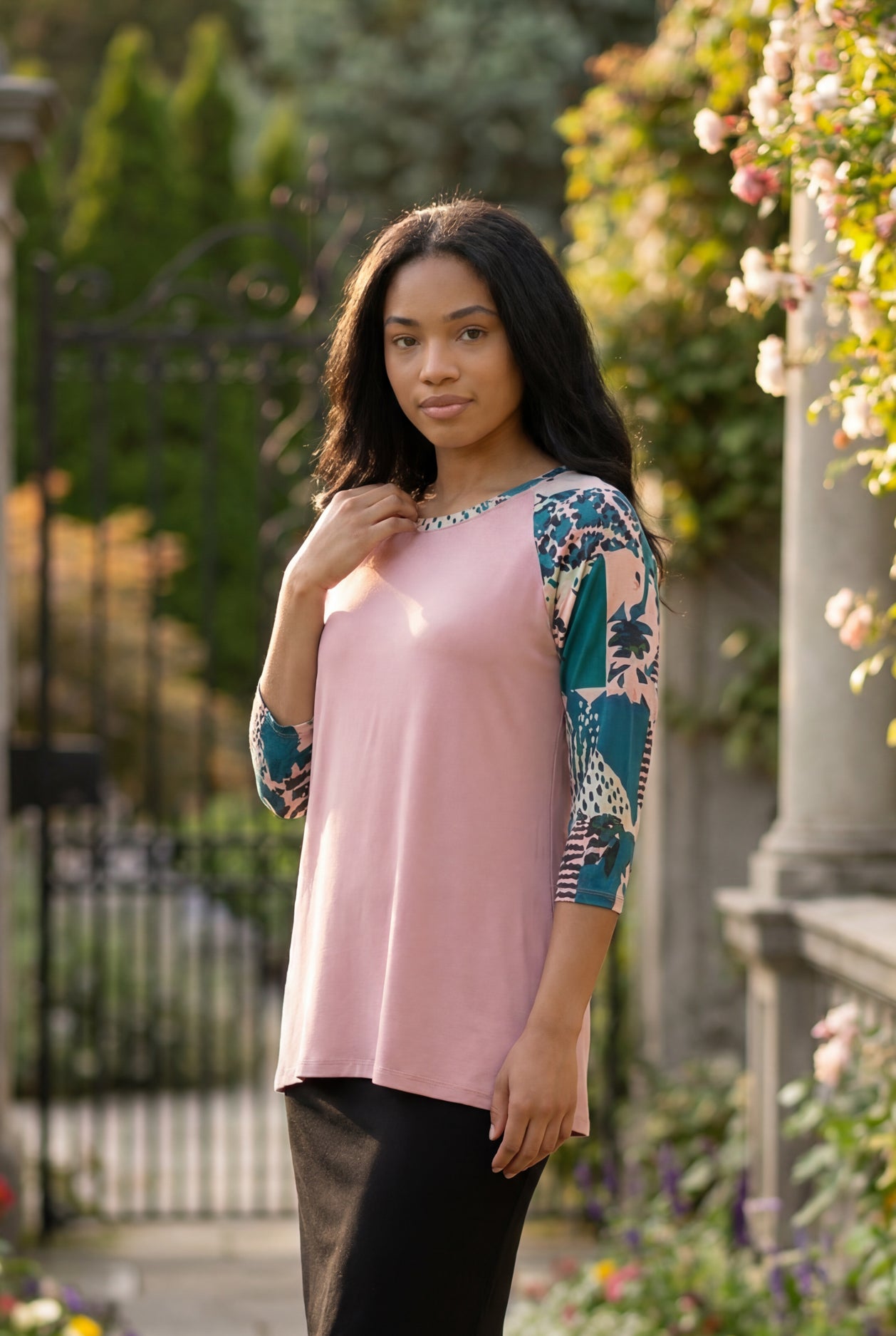 Woman in a garden wearing a floral top and black skirt