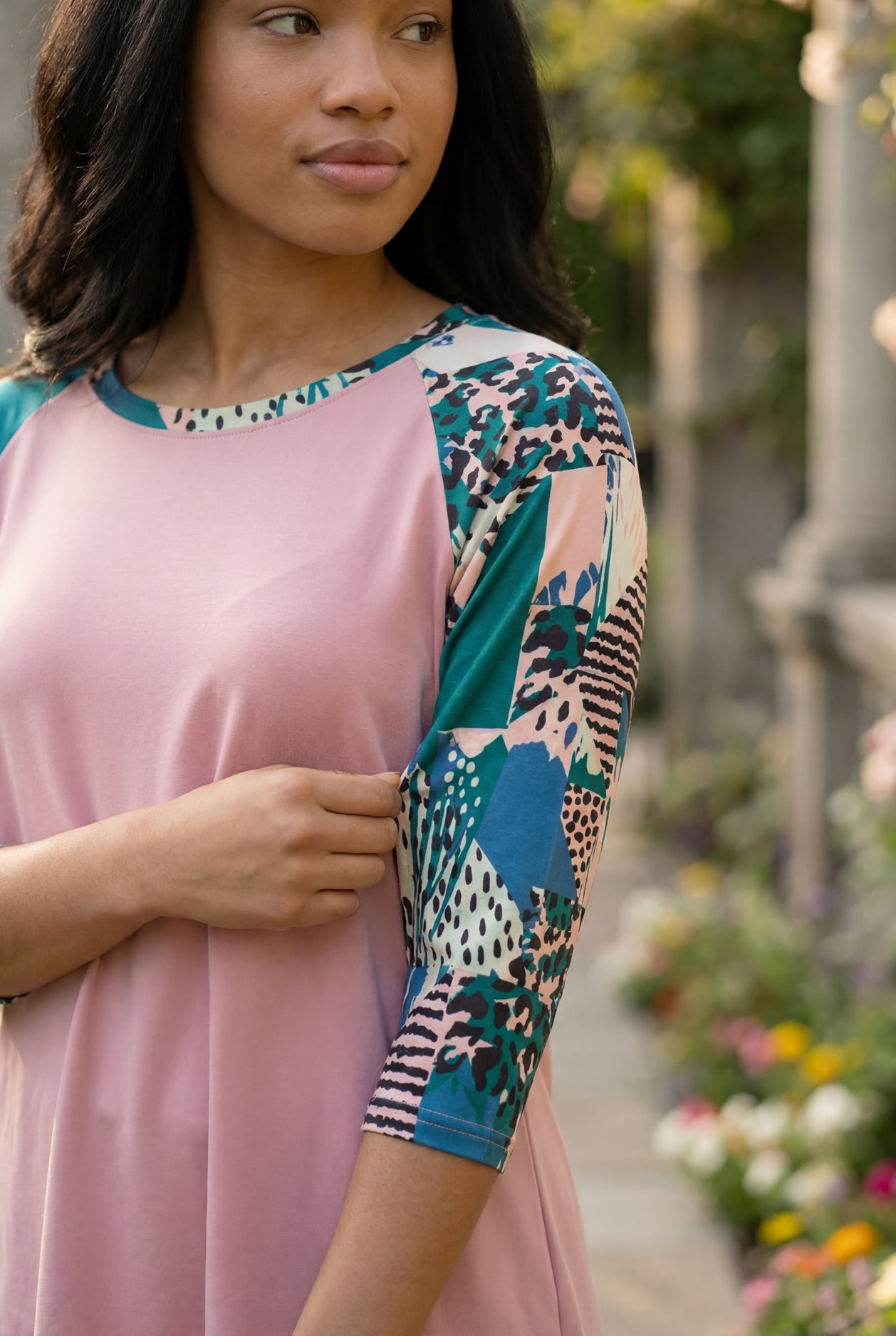 Woman in a garden wearing a floral top and black skirt