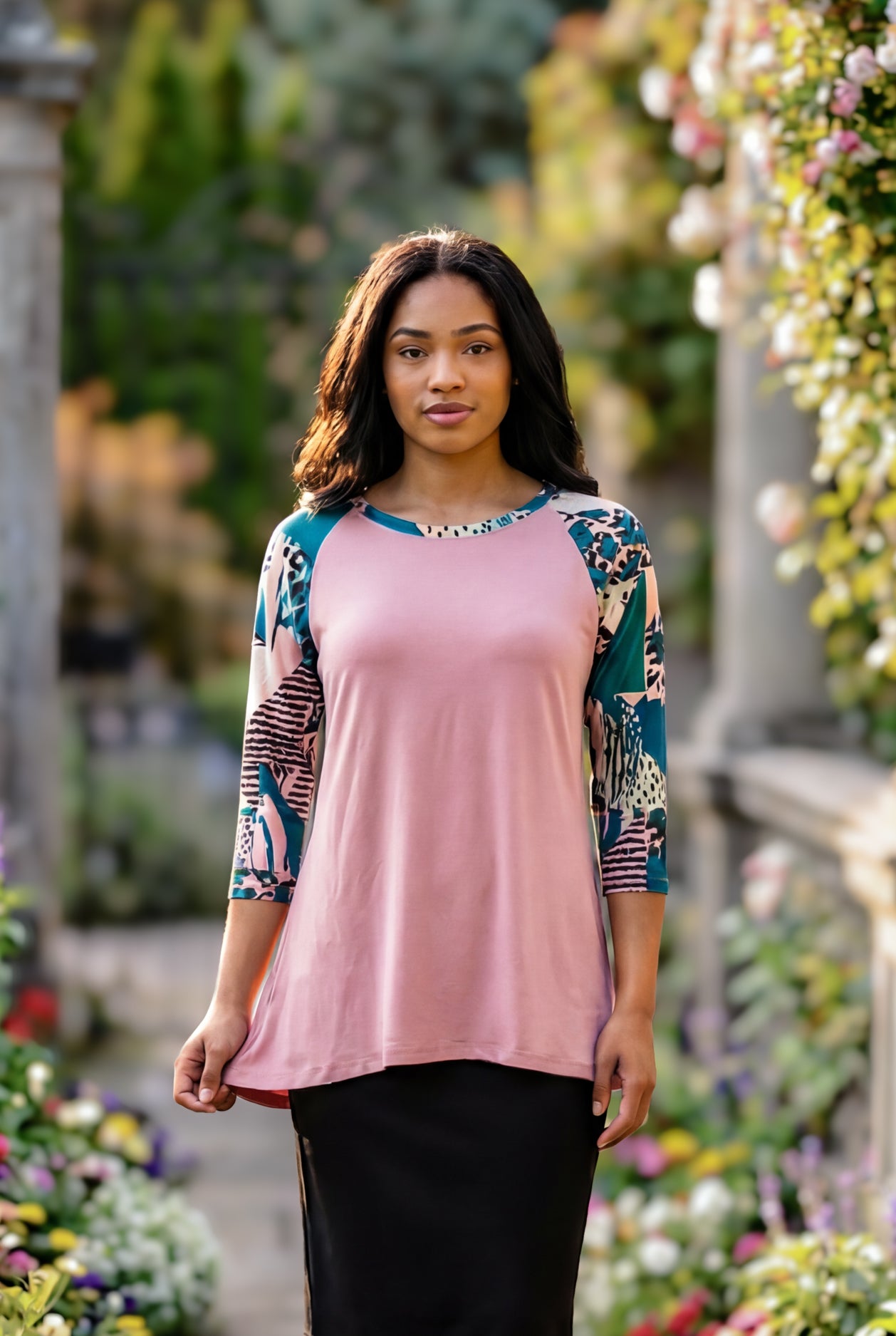 Woman in a garden wearing a floral top and black skirt