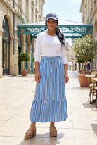 A women wearing a veritcal blue and white striped maxi skirt.