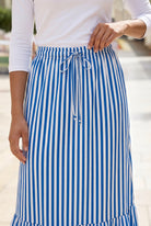 A women wearing a veritcal blue and white striped maxi skirt.