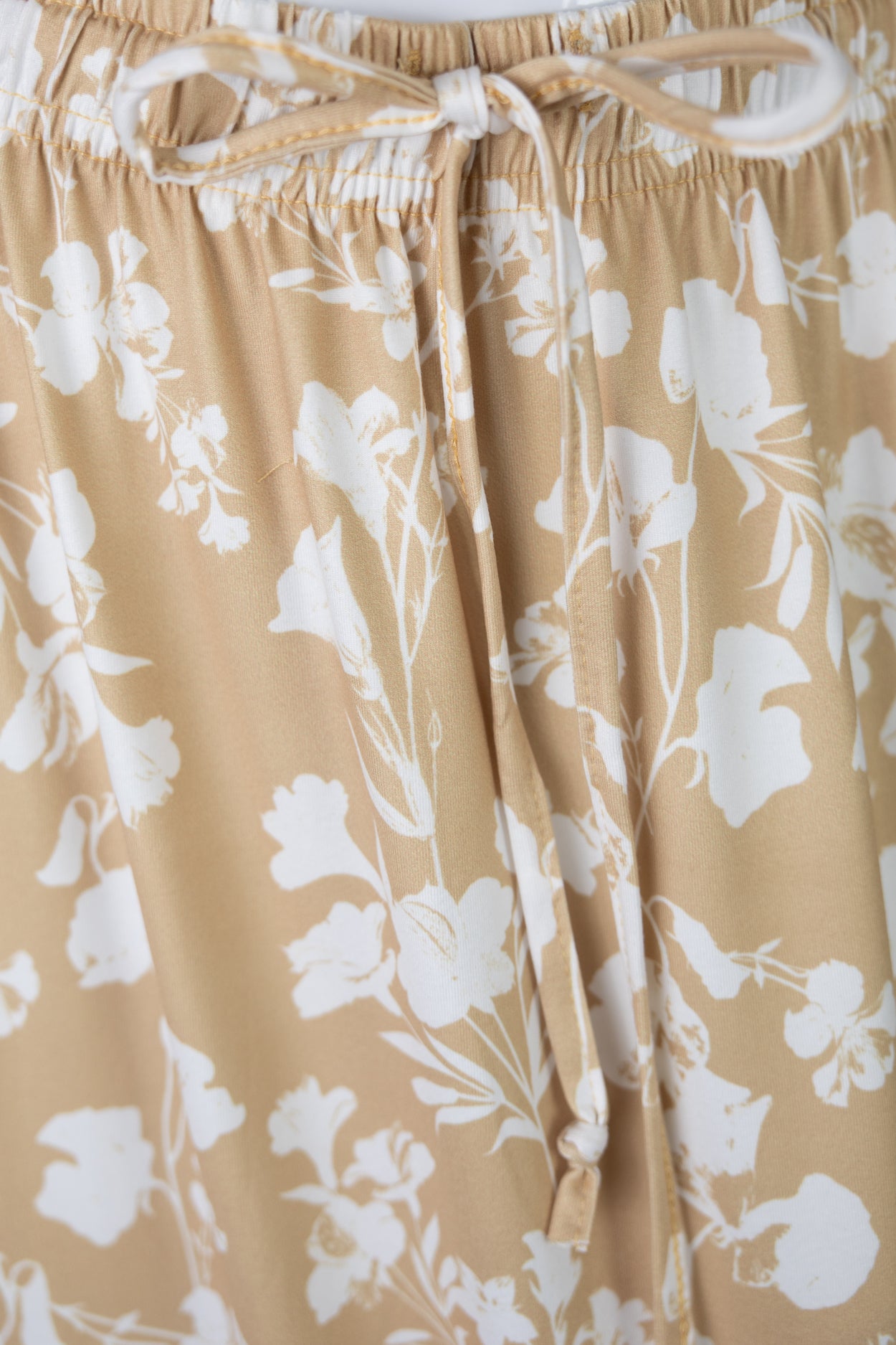 Closeup Shot of the tie of the waistband on a yellow floral skirt.