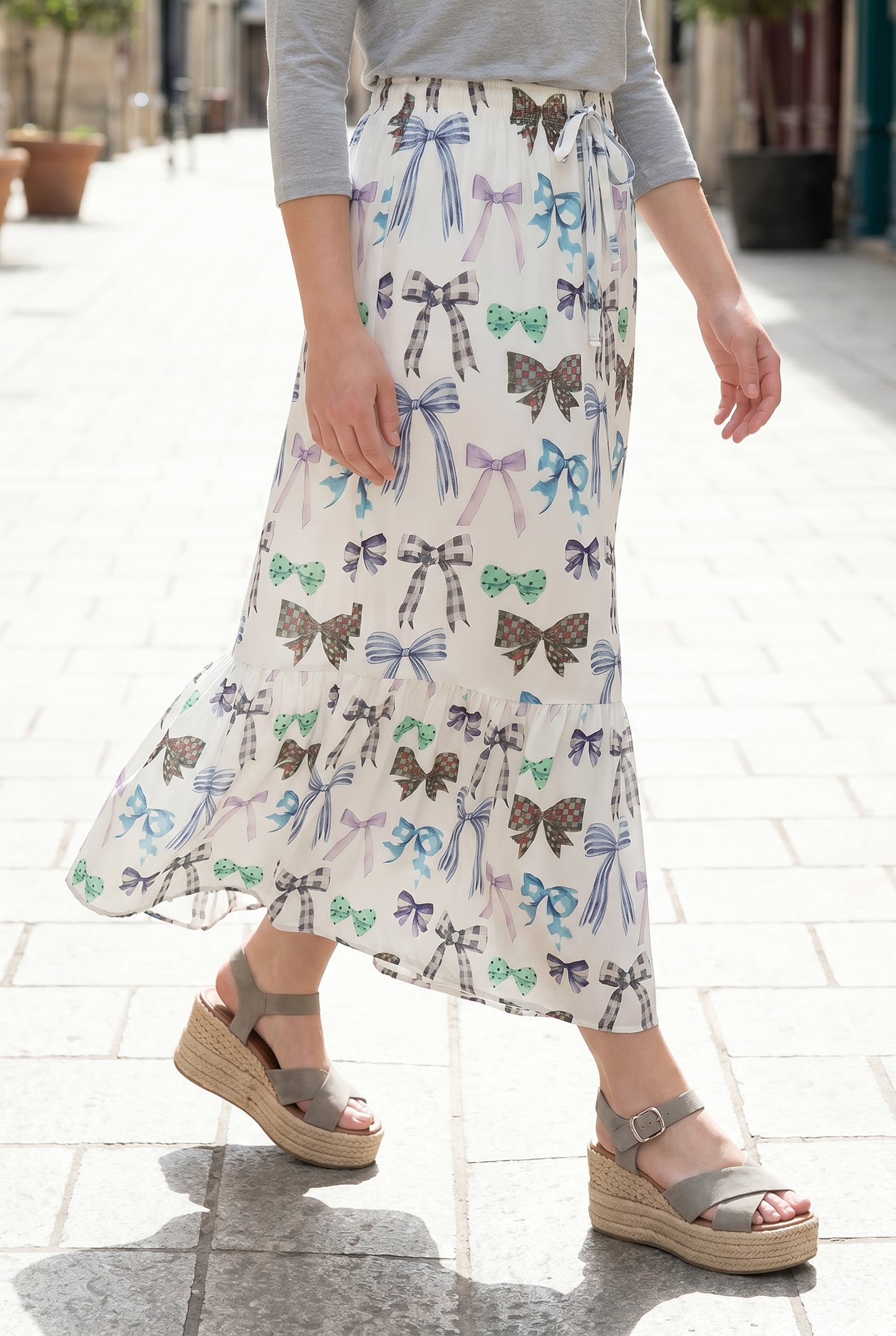 Person wearing a maxi skirt with a bow pattern. 