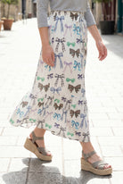 Person wearing a maxi skirt with a bow pattern. 