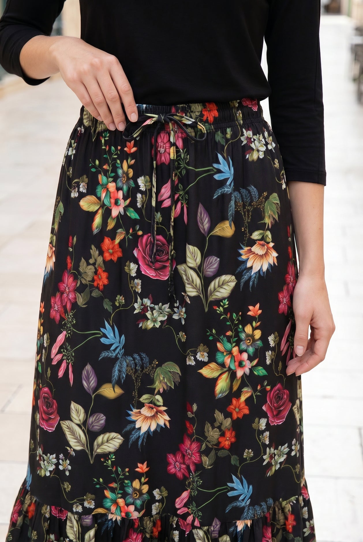 Person wearing a black floral skirt with a white background