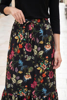 Person wearing a black floral skirt with a white background