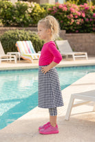 A picture of a young girl beside a pool with a beach ball wearing a modest skort with a coordinating hot pink shirt.