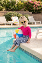A picture of a young girl beside a pool with a beach ball wearing a modest skort with a coordinating hot pink shirt.