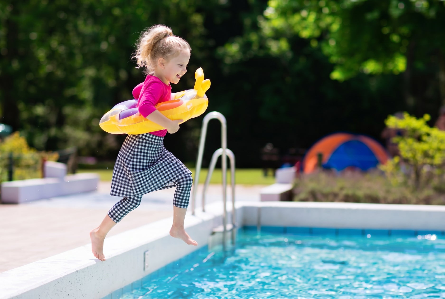 Child with a yellow inflatable ring jumping into a pool