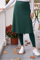 Nuggles® Tilly Sport Skirt in Teal Green, waist-down front view with one hand on the porch railing and white sneakers