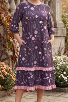 Nuggles® Patricia Dress in Twilight Garden, both hands in the side pockets above the pink ruffle trim