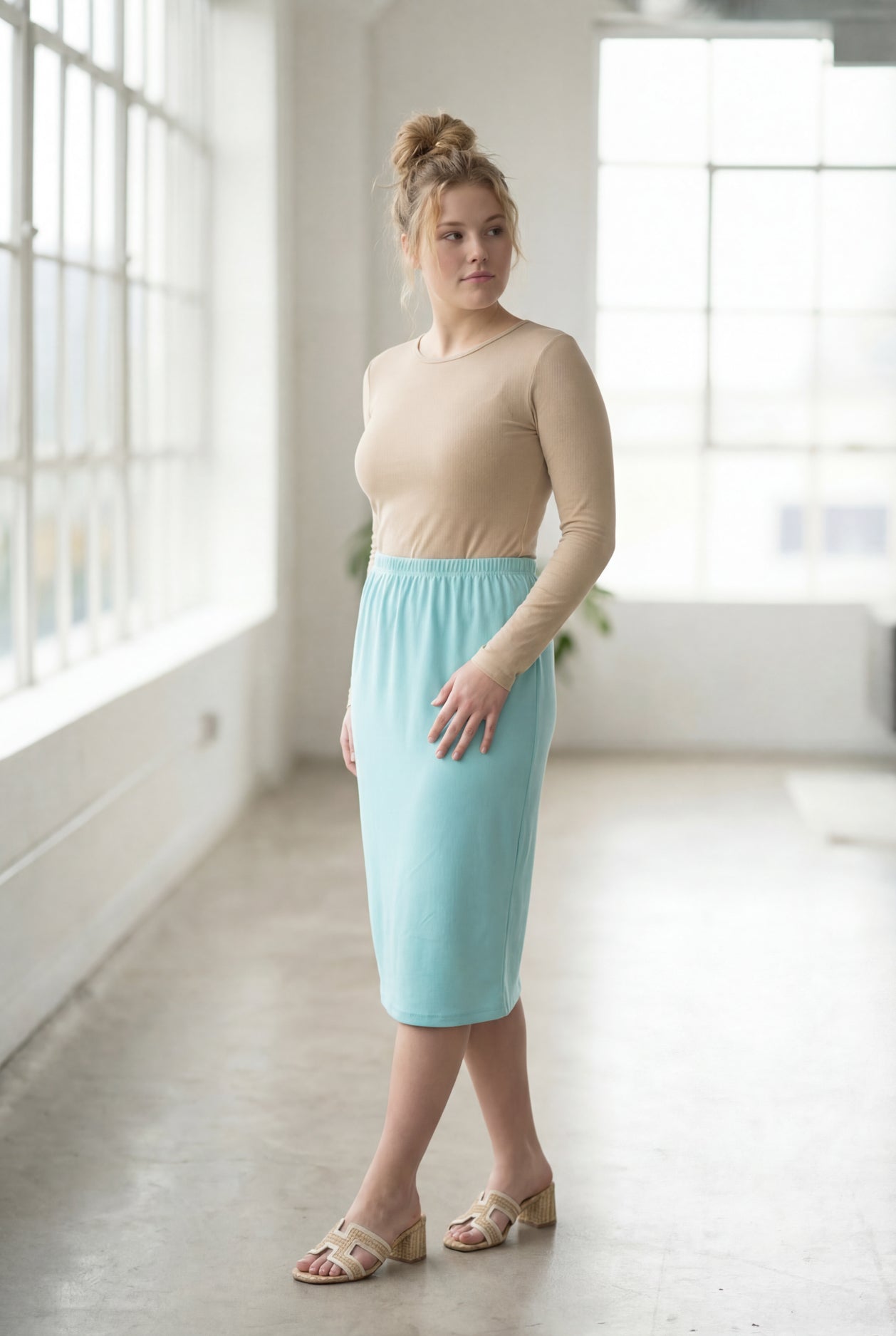 Women wearing a aqua blue classic 27" midi length skirt with a beige shirt in a sunlight loft.
